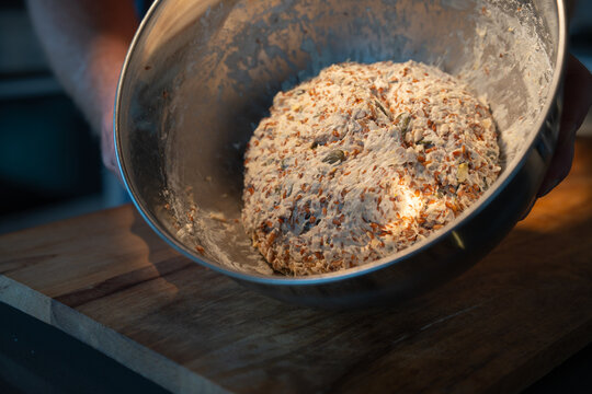 Dough preparation for a rustic grain bread. Mixing ingredients in a bowl. Close-up.