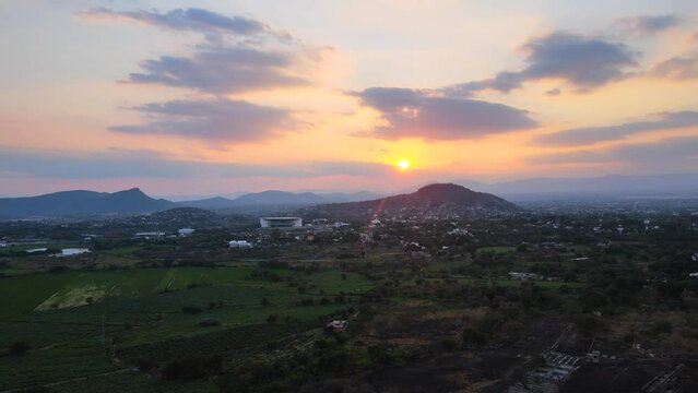 Incredible aerial view of a sunset in rural Mexico. Drone video captured in 4K of a cloudy sunset with background mountains in Cuernavaca, Morelos. The building of Tec de Monterrey can be spotted.