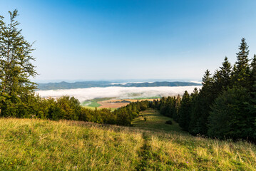 Fototapeta na wymiar Rajecka dolina valley coverred vy fog with hills of Sulovske vrchy mountains on the background from meadow bellow Baba hill summit in Mala Fatra mountains in Slovakia
