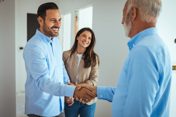 Happy couple buying a new home and handshaking with their real estate agent. Estate Agent Greeting...