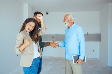 Fototapeta premium Happy couple buying a new home and handshaking with their real estate agent. Estate Agent Greeting Couple During Visit To New Home. Couple house property agent home real estate 