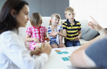 Adults and children sit around a table on which playing cards are located boy argues and discusses...