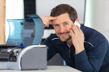 man repairing printer makes a telephone call