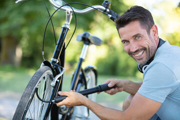 cheerful man inflating bicycle tyre
