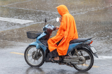 Fototapeta na wymiar A man dressed in a raincoat rides a motorcycle in the heavy rain
