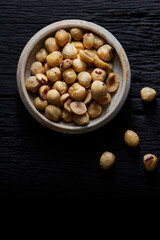 Hazelnut in small cup on black wooden background.