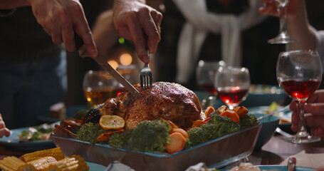 Close up shot of people eating delicious roasted turkey during thanksgiving or christmas dinner party, filling up plates and glasses - food and drink, celebration 