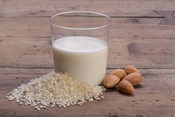 rice and almond milk in glass cup with pile of white rice on rustic wooden table