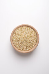 brown rice in wooden bowl on white background shot from above