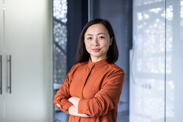 Portrait of a young beautiful confident Asian businesswoman standing in an office center with her...