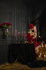 Luxury candlelight dinner setup for couple on Valentine's day. Romantic date. Setting table in restaurant. Location decoration red flowers, decor candles for surprise marriage proposal. Closeup detail