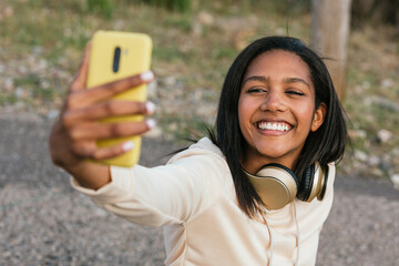 Ethnic woman on longboard taking selfie on smartphone