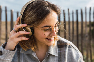 Happy young lady listening to music in headphones in countryside