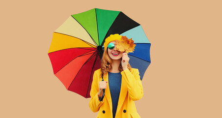 Autumn color style outfit, beautiful smiling young woman holds yellow maple leaves with colorful...