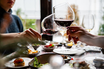 Close up of hands young couple man and woman clinking with glasses of red wine at restaurant