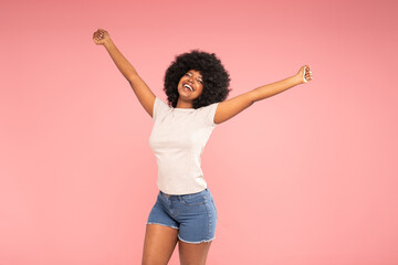 Optimistic african american woman dancing, laughing happily.  Girl with afro hairstyle wearing casual tshirt and short jeans
