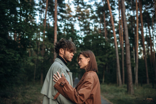 young couple in love in a fashionable coat walks through the forest. Autumn gloomy mood and a beautiful couple of models. Cinematic image