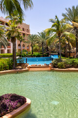 Swimming pool with clear water surrounded by palm trees in one of the best resorts