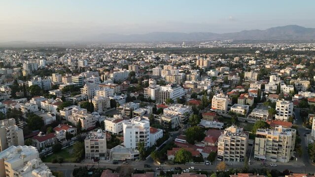 Drone flight over residential neighborhood in South Nicosia, with a view towards the Northern part of the city and mountains in the background
