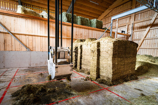 Moderner F&uuml;tterungsroboter,Kran zur Bef&uuml;llung im Futterlager greift nach Grassilage.