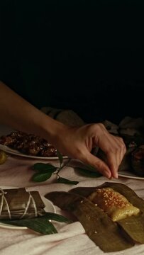 Vertical view of adding roasted coconut pieces toppings to a suman latik or steamed glutinous rice wrapped in banana leaf, an authentic traditional dessert from the Philippines