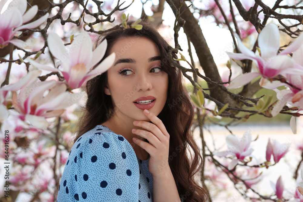 Poster Beautiful woman near blossoming magnolia tree on spring day