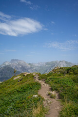 small path on top of a mountain with view towards alpine summits and sky