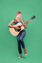 Happy hippie woman playing guitar on green background