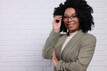 Young businesswoman in eyeglasses near white brick wall. Space for text