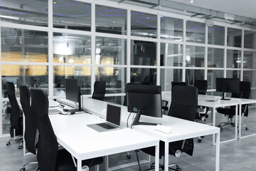 Stylish interior of open plan office. Workspace with computers, tables and chairs
