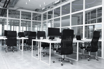 Stylish interior of open plan office. Workspace with computers, tables and chairs