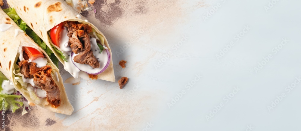 Poster fresh roll of grilled meat and salad wrapped in tortilla with white sauce isolated pastel background