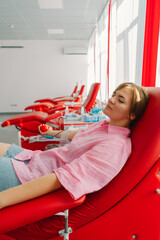 Young woman making blood donation in hospital. A woman donates blood while holding a red heart....