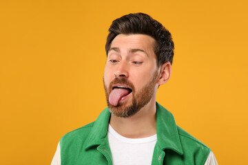 Man showing his tongue on orange background