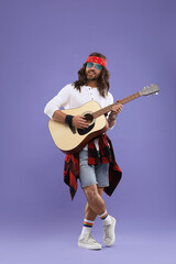 Obraz premium Stylish hippie man in sunglasses playing guitar on violet background