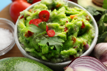 Delicious guacamole and ingredients on table, closeup