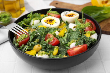 Delicious salad with pesto sauce and fork on white tiled table, closeup