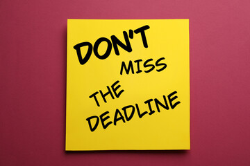 Note with reminder Don't Miss The Deadline on burgundy background