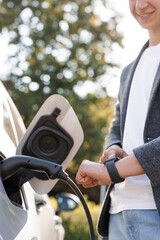 Unrecognizable man plugging in charging cable to to electric vehicle. Male hand inserts power...