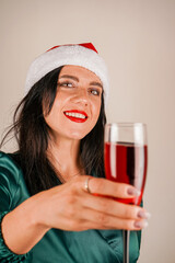A young brunette girl in a red cap of Santa's assistant. Christmas advertisement. The winter holidays. Beautiful girl with a glass in her hands.