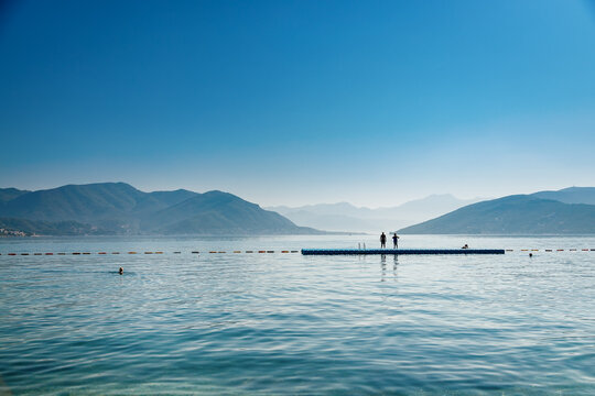 Sunny view of the bay of Kotor with a pontoon for swimming people in the sea