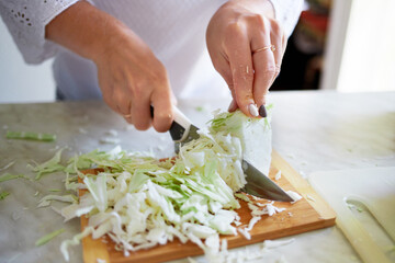 A girl cuts cabbage in the kitchen at home. Healthy eating at home.