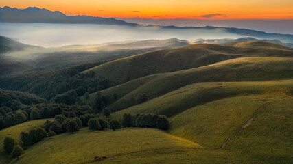 Fototapeta premium Mountain panorama with fog and green meadows. Clouds at sunrise