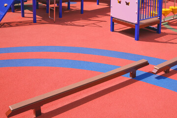 Kids balance beams with playground equipment on colorful orange and blue rubber floor in...