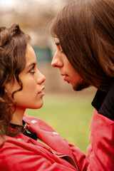 multiracial heterosexual couple of alternative and rock look looking into each other's eyes in affectionate attitude in a park in autumn. love and relationships. complicity