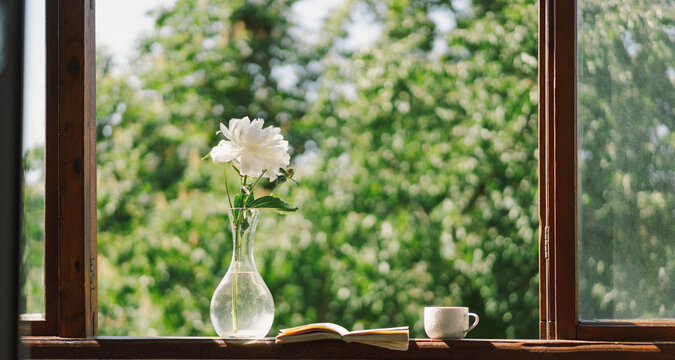Book, cup coffee and white peonies on a wooden window. Romantic concept. Vintage style