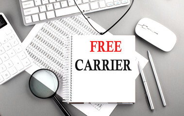 FREE CARRIER text on notepad on chart with keyboard and calculator on grey background