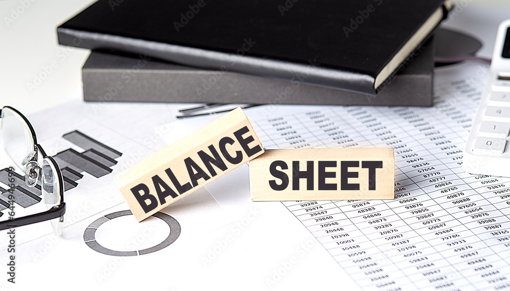 Poster balance sheet - text on a wooden block with chart and notebook