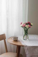A bouquet of asters in a glass vase, a cup of coffee on a round table in the living room