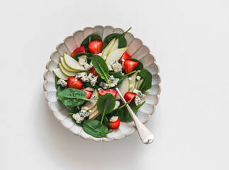 Pear, spinach, gorgonzola cheese, strawberry salad on a light background, top view